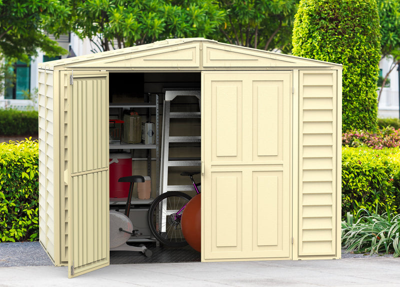 Duramax Duramate 8'x5.3' Vinyl Shed with one door open, set in a lush garden, showcasing interior space and sturdy design.