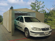 A car exiting the Duramax Vinyl Garage 10.5x15.5 that is placed outdoors.