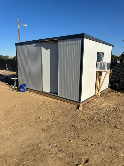 Duramax Insulated Glass Building 13'x10' - 32003 shown on a dirt construction site with an AC unit and tools around the structure.