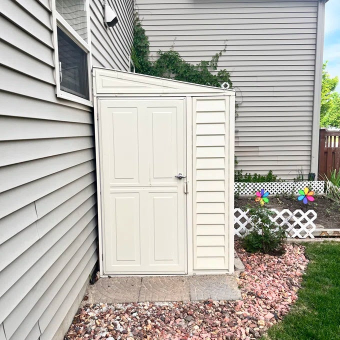 Duramax SideMate Shed with Foundation 4'x8' (06625) installed in a narrow side yard with stone landscaping and a garden backdrop.